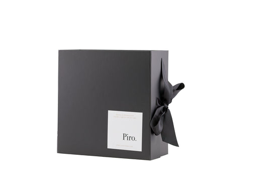 Olio Piro gift box with a white label on the front, adorned with a black ribbon, containing custom selections of Olio Piro and Bonini Balsamic  premium olive oil bottles
